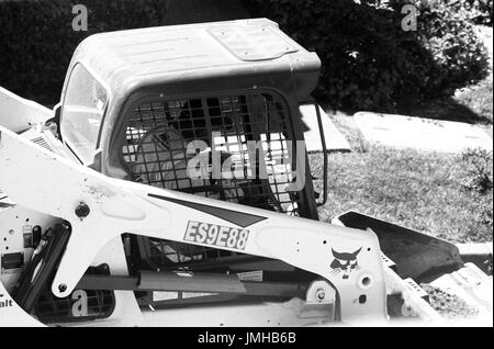 Un lavoratore edile utilizza un caricatore a estremità anteriore per sollevare un mucchio di asfalto polverizzato in un cantiere, San Ramon, California, 26 giugno 2017. Foto Stock