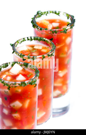 Campionatori di gazpacho Servito in alti bicchierini con un cerchio di coriandolo isolato su uno sfondo bianco Foto Stock
