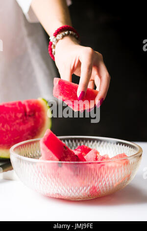 Donna prendendo anguria fetta da una ciotola di vetro Foto Stock