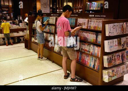 Molti giovani adulti la lettura di libri sugli scaffali, cercando il libro perfetto per acquistare dal bookstore di Taipei, Taiwan. Foto Stock