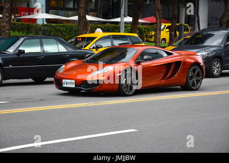 Orange nuova McLaren aziona verso il basso una strada principale di Taipei, Taiwan, causando a tutti di girare e guardare. Foto Stock