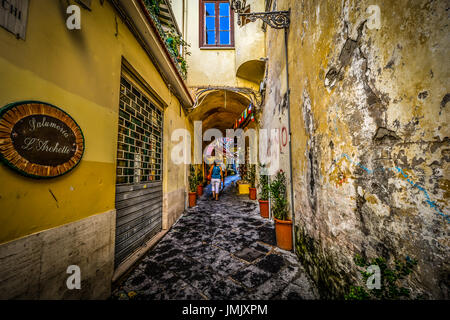 Una donna che viaggia da sola cammina giù per un sentiero stretto attraverso un piccolo tunnel nella città mediterranea di Sorrento Italia Foto Stock