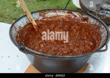 Una grande ciotola di chili con carne in una ghisa pentola cotta su un fuoco aperto Gower Chili Festival Glamorgan Galles Foto Stock