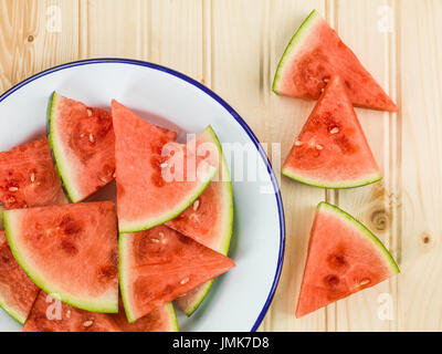 Piastra di tagliare segmenti di cocomero contro un pino di luce sullo sfondo di legno Foto Stock