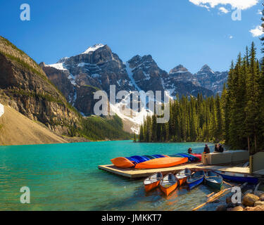 Canoe su un molo al Lago Moraine nel Parco Nazionale di Banff, Alberta, Canada, con cime innevate della Canadian Rocky Mountains in background. Foto Stock