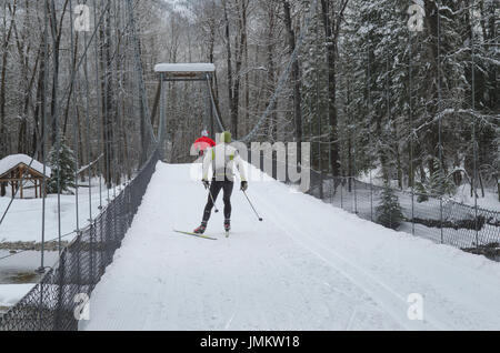 I fondisti sulla sospensione ponte sul fiume Methow in inverno, North Cascades Washington Foto Stock