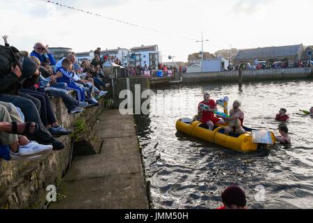 West Bay, Dorset, Regno Unito. Il 27 luglio 2017. RNLI annuale gara zattera sul fiume Brit alla stazione balneare di West Bay nel Dorset. I concorrenti spruzzare la folla a guardare la gara con le pistole ad acqua. Credito Foto: Graham Hunt/Alamy Live News Foto Stock