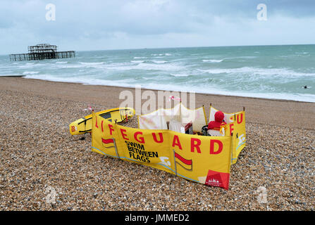 Brighton, Regno Unito. 28 Luglio, 2017. Alta venti ha colpito la costa sud dell'Inghilterra. Un bagnino sondaggi una spiaggia deserta. Credito: Brian Minkoff/Alamy Live News Foto Stock