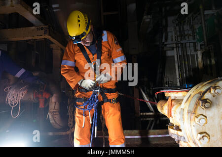 Una corda industriale tecnico accesso impostazione di cablaggio, sul petrolio del Mare del Nord e l'installazione di gas indossando tute arancioni. Credito: LEE RAMSDEN / ALAMY Foto Stock