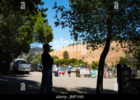 La silhouette di un uomo attraversando le sue braccia è visibile come egli guarda verso la marina al Lago Chabot parco regionale, un East Bay Regional Park, in Castro Valley, California, 4 luglio 2017. Foto Stock