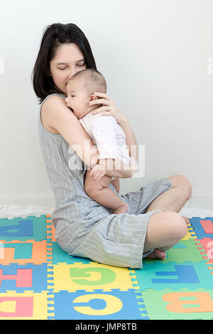 Ritratto di felice madre asiatica mentre tiene il suo piccolo grazioso baby in schiuma eva in camera da letto Foto Stock