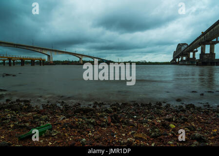 Su strada e su rotaia brdiges sulle rive di un fiume. Bottiglia di birra gettato sulla riva. Foto Stock
