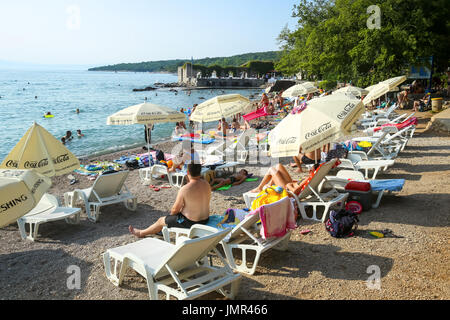 Gnivizze, Croazia - 24 Giugno 2017 : Persone rilassarsi sulle sedie a sdraio sotto gli ombrelloni e il nuoto nel mare Adriatico in Njivice Croazia. Foto Stock
