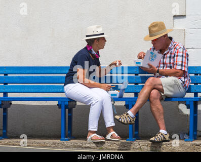 Coppia seduta sul banco di mangiare pesce e patatine a Lyme Regis, Dorset in luglio Foto Stock