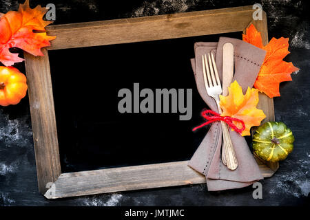 In autunno il concetto di menu - tavolo rustico posto impostazione con una forchetta e un coltello avvolto in un tovagliolo con caduta stagione foglie decorative e zucche con chal Foto Stock