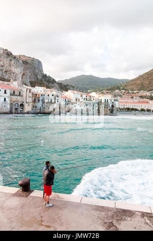 Turismo e vacanze Perla di Sicilia, due pescatori nella piccola città di Cefalù a sunrise, Sicilia, Italia meridionale, con vista sul mare Foto Stock