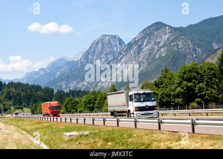 Autocarri che passano sullo sfondo di alta montagna in Austria Foto Stock