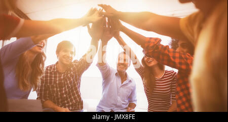 Il gruppo di allegro la gente di affari dando alta cinque seduti ufficio creativo Foto Stock