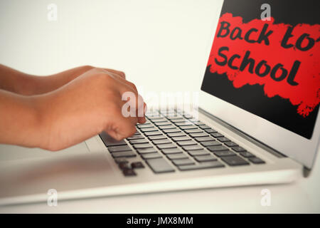 Si torna a scuola il testo su splash rosa contro schoolboy utilizzando laptop Foto Stock