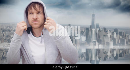 Ritratto fiduciosi, raffreddare i giovani latino uomo felpa con cappuccio da indossare contro la camera con ampia finestra con vista sulla città Foto Stock