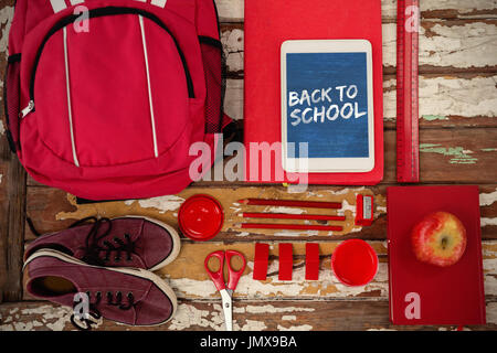 Immagine grafica di rosso si torna a scuola il testo contro la vista aerea del sacchetto e tavoletta digitale su tavola Foto Stock