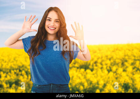 Ritratto di felice moda femminile modello gesti contro la vista panoramica di giallo senape campo Foto Stock