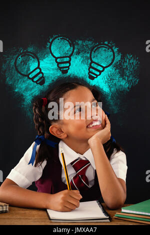 Digital immagine composita di lampadine su Blu Vernice spray contro schoolgirl facendo il suo dovere contro la lavagna Foto Stock