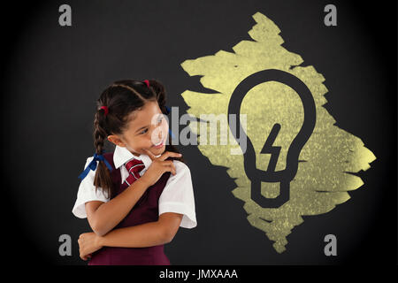 Lampadina della luce sul nero scarabocchi contro schoolgirl in piedi contro la lavagna in aula Foto Stock
