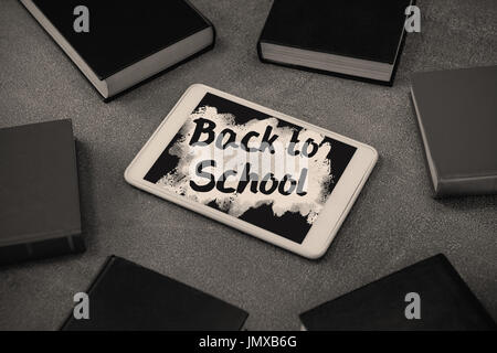 Si torna a scuola il testo su splash rosa contro la tavoletta digitale circondato con colorati organizzatori sulla lavagna Foto Stock