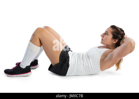 Vista laterale di atleta femminile praticando sit ups contro uno sfondo bianco Foto Stock