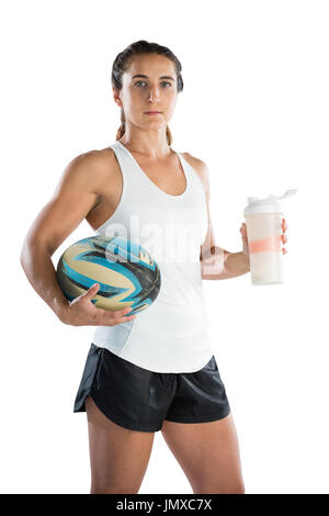 Ritratto di donna giocatore di rugby con la palla e la borraccia in piedi contro uno sfondo bianco Foto Stock
