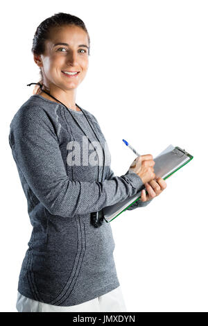 Ritratto di rugby sorridente coach iscritto sulla clipboard mentre in piedi contro uno sfondo bianco Foto Stock