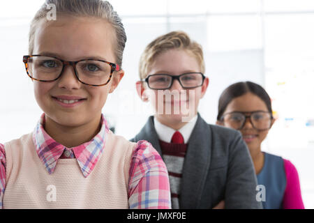 Ritratto di bambini come business executive sorridere mentre in piedi in ufficio Foto Stock