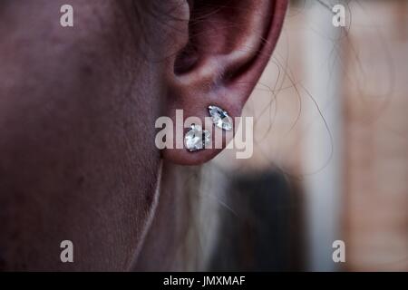 Testa di donna con due piccoli orecchini in un orecchio. Close-up concetto umano. Foto Stock