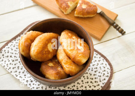 Tradizionali fatti in casa polpette fritte o torte in un vaso di ceramica. Russo fritti crostate di pasta lievitata in uno stile rustico. Foto Stock