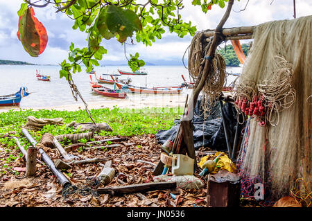 Rawai, Tailandia - 27 ottobre 2013: reti da pesca & affrontare appendere a Rawai Beach & tradizionale e lungo-coda di barche ormeggiate off-shore sulla punta meridionale di Phuket Foto Stock