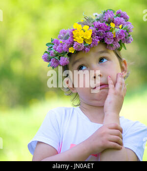 Bambina con una ghirlanda di fiori sul suo capo facendo una buffa faccia Foto Stock