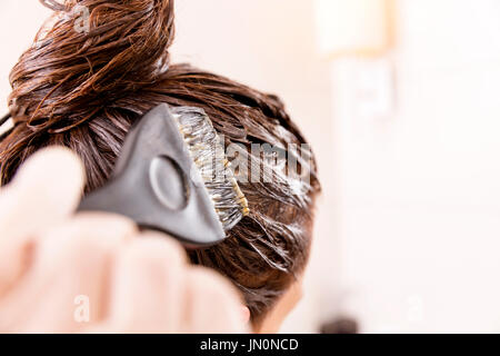 Donna con morire i suoi capelli nella parte anteriore dello specchio nel suo proprio bagno. Foto Stock