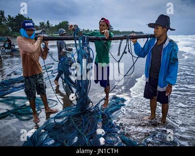 Airkuning, Bali, Indonesia. 29 Luglio, 2017. I pescatori roll up della rete dopo alaggio in in Kuning, un musulmano villaggio di pescatori sull'angolo sud-ovest di Bali. Gli abitanti di un villaggio detto loro regolare delle catture di pesce è stato in diminuzione per diversi anni e che sono alcune mattine che tornano a riva con aver catturato un pesce. Credit: Jack Kurtz/ZUMA filo/Alamy Live News Foto Stock