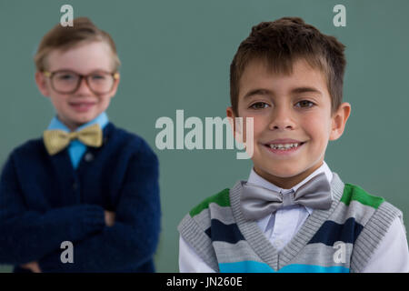 Ritratto di bambini come business executive sorridere mentre in piedi in ufficio Foto Stock