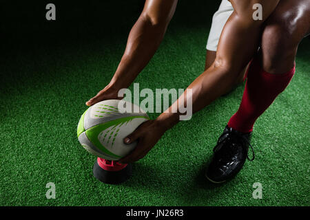 Angolo di alta vista sportivo mantenendo il pallone da rugby sul raccordo a T sul campo Foto Stock