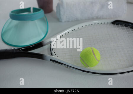 Angolo di alta vista della palla da tennis sulla racchetta da aletta parasole contro uno sfondo bianco Foto Stock