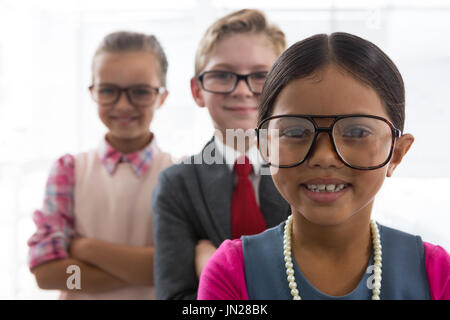Ritratto di bambini come business executive sorridere mentre in piedi in ufficio Foto Stock