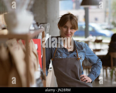 Ritratto di sorridente cameriera in piedi in cafe Foto Stock