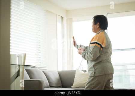 Vista laterale del senior donna esercizio permanente, mentre a casa Foto Stock