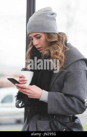 Donna che utilizza il cellulare mentre in piedi dalla pole in città Foto Stock