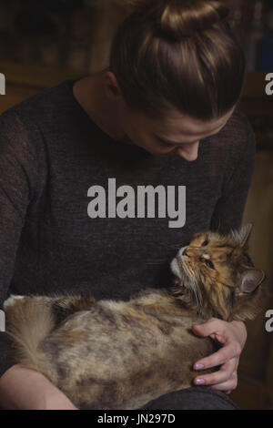 Close-up di donna che mantiene il suo gatto di casa in casa Foto Stock