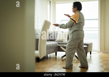 Per tutta la lunghezza della donna senior esercizio permanente, mentre a casa Foto Stock