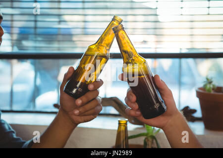 Close-up di amici di tostatura di bottiglie di birra Foto Stock