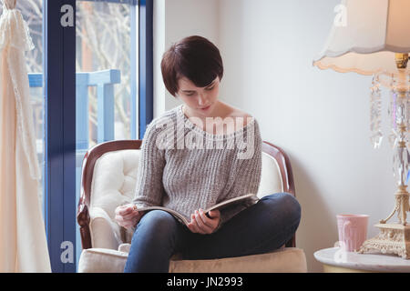 Giovane donna leggendo una rivista a casa Foto Stock